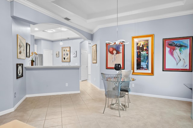 tiled dining space featuring ornamental molding and a tray ceiling