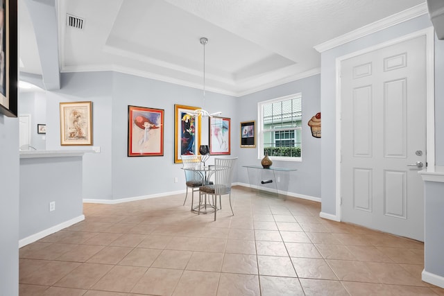 tiled dining space featuring crown molding, a textured ceiling, and a tray ceiling