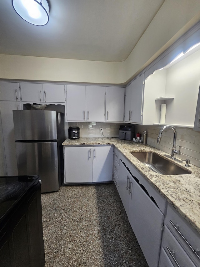 1105 Sunrise Blvd, Fort Pierce, FL 34950 - kitchen with a sink, freestanding refrigerator, light stone countertops, decorative backsplash, and black range with electric cooktop