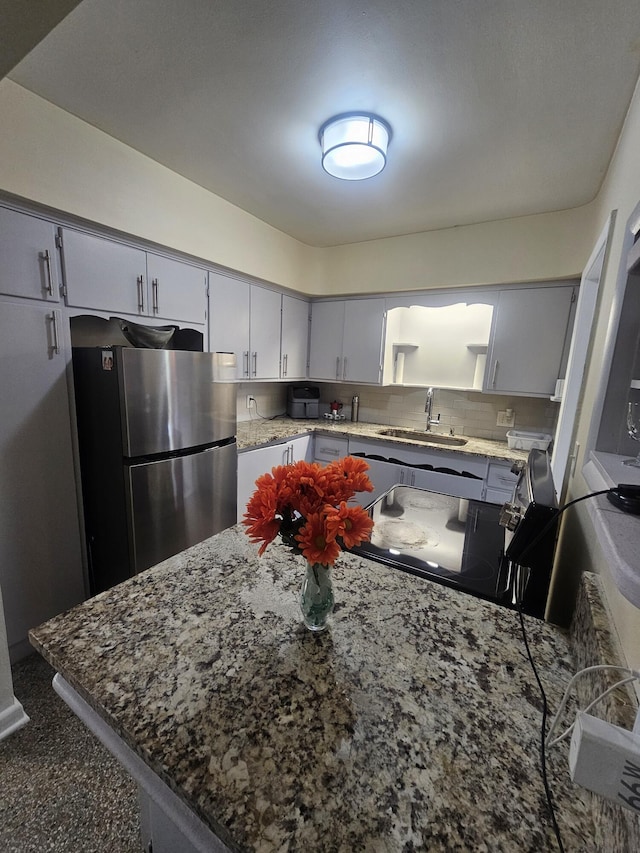 1105 Sunrise Blvd, Fort Pierce, FL 34950 - kitchen with backsplash, freestanding refrigerator, light stone countertops, and a sink