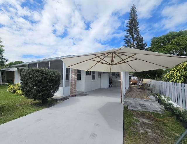 exterior space featuring concrete driveway, a carport, and fence