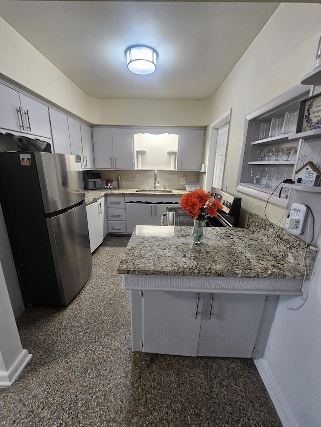 1105 Sunrise Blvd, Fort Pierce, FL 34950 - kitchen featuring light stone counters, a sink, a peninsula, baseboards, and freestanding refrigerator