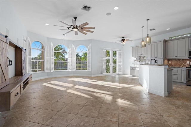 unfurnished living room with light tile patterned flooring, sink, and ceiling fan