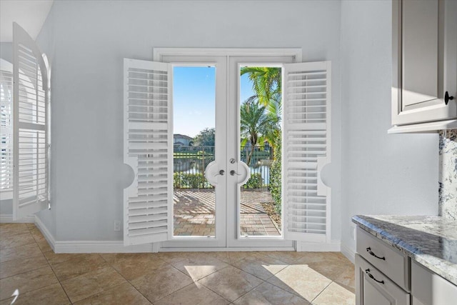 entryway featuring a water view, light tile patterned flooring, and french doors