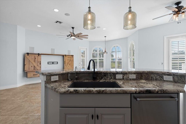 kitchen featuring gray cabinetry, sink, hanging light fixtures, and a barn door