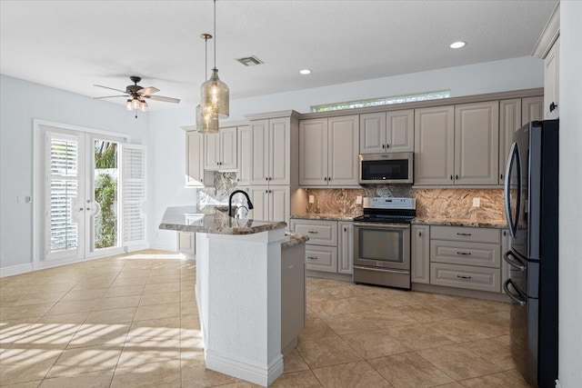 kitchen with appliances with stainless steel finishes, decorative light fixtures, light tile patterned floors, and decorative backsplash