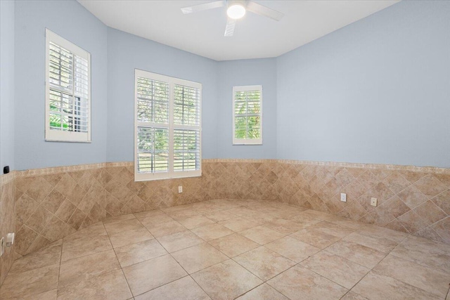 tiled empty room with tile walls and ceiling fan