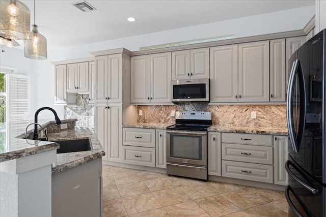 kitchen featuring sink, appliances with stainless steel finishes, tasteful backsplash, light stone countertops, and decorative light fixtures