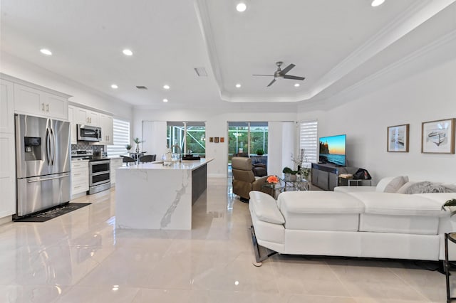 living room with ornamental molding, a raised ceiling, and ceiling fan