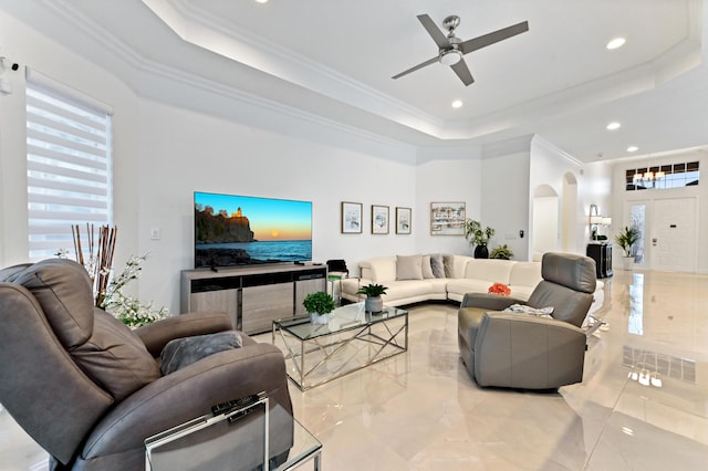 living room with a healthy amount of sunlight, ornamental molding, and a tray ceiling