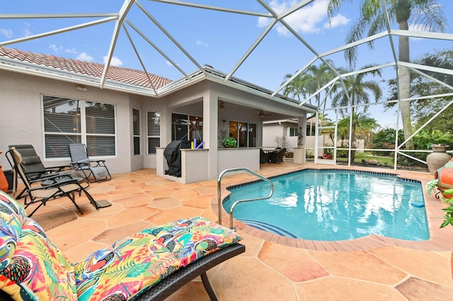 view of swimming pool with ceiling fan, glass enclosure, and a patio area