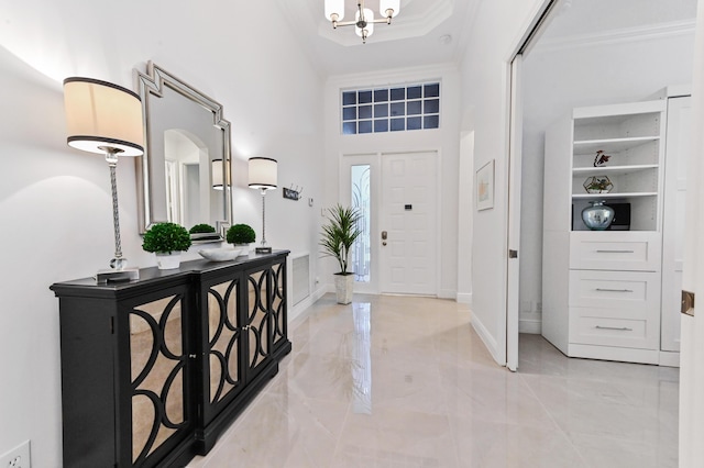 foyer entrance with crown molding, a towering ceiling, and a notable chandelier