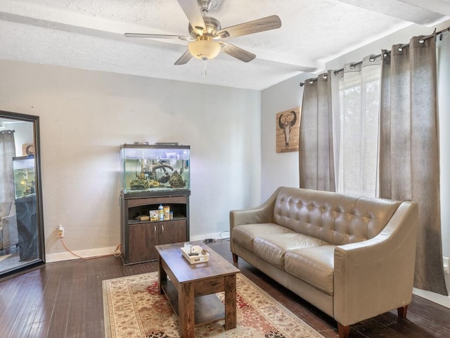 living room featuring ceiling fan, dark wood-type flooring, and a textured ceiling