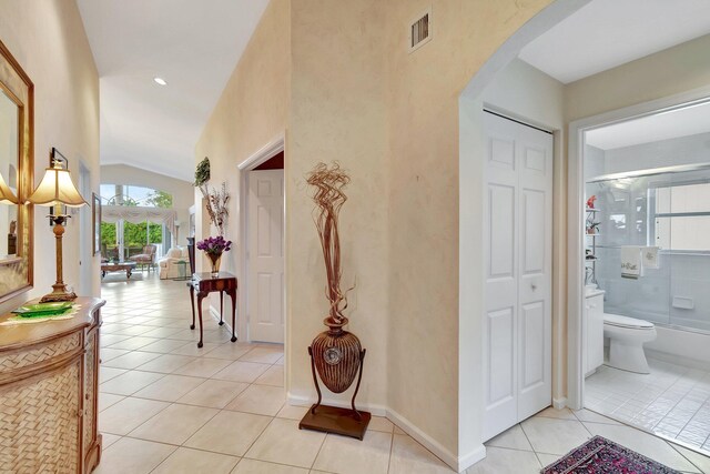 hallway featuring light tile patterned flooring and high vaulted ceiling