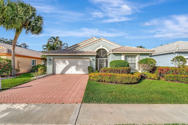 view of front of home with a front yard, stucco siding, a garage, a tile roof, and decorative driveway