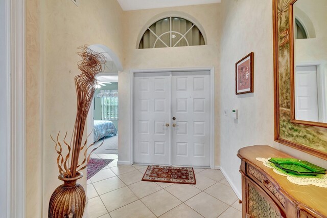 hall with beam ceiling, a high ceiling, and light tile patterned floors