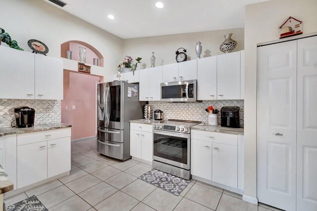 kitchen with kitchen peninsula, pendant lighting, stainless steel appliances, light stone countertops, and white cabinets