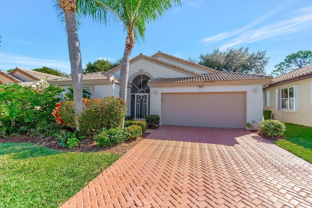 mediterranean / spanish-style home with stucco siding, decorative driveway, a garage, and a tiled roof