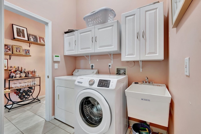 laundry area featuring sink, light tile patterned floors, cabinets, and washing machine and clothes dryer