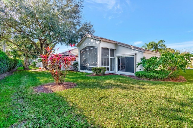 rear view of property with a lawn and a sunroom