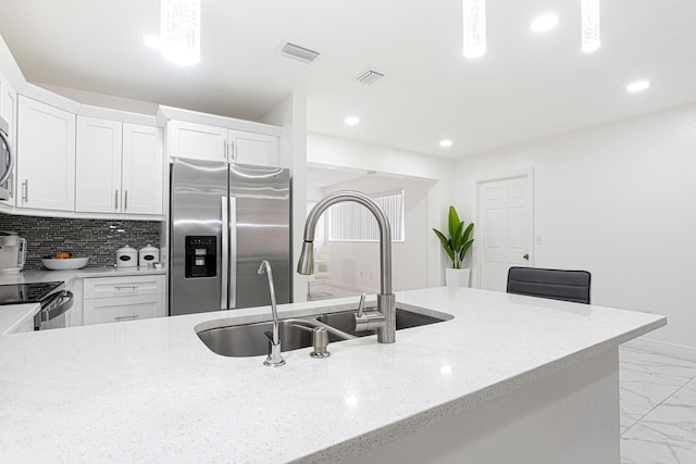 kitchen featuring sink, white cabinets, decorative backsplash, stainless steel appliances, and light stone countertops