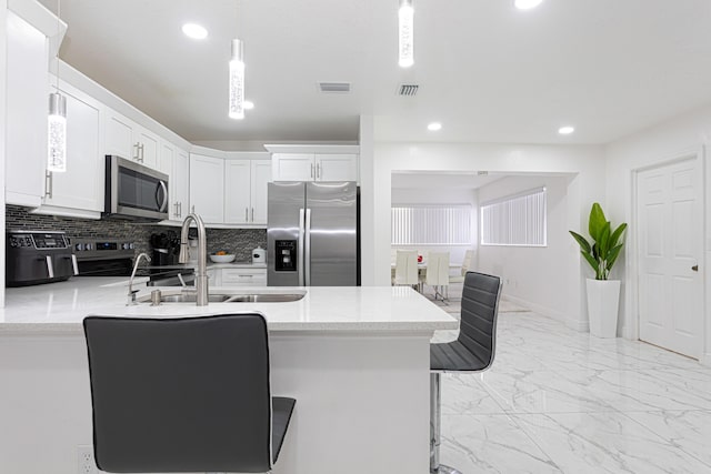 kitchen featuring white cabinetry, sink, stainless steel appliances, and a kitchen bar