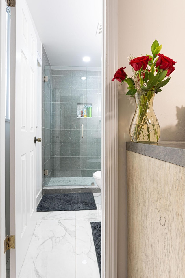 bathroom with toilet and a shower with door