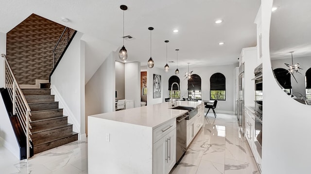 kitchen featuring a large island, sink, appliances with stainless steel finishes, white cabinetry, and hanging light fixtures