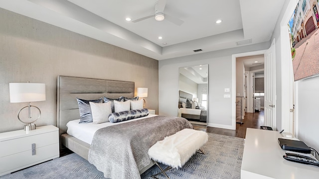 bedroom featuring ceiling fan, wood-type flooring, and a raised ceiling