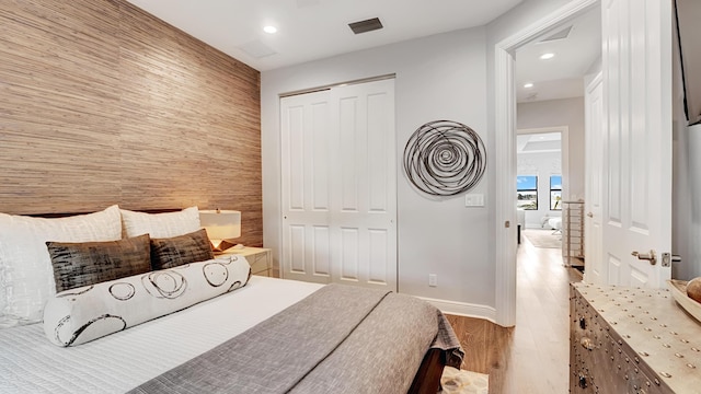 bedroom with wooden walls, light hardwood / wood-style floors, and a closet