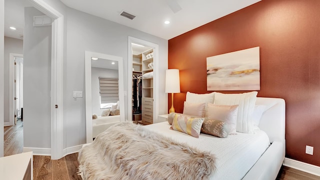 bedroom featuring hardwood / wood-style flooring, a walk in closet, and a closet