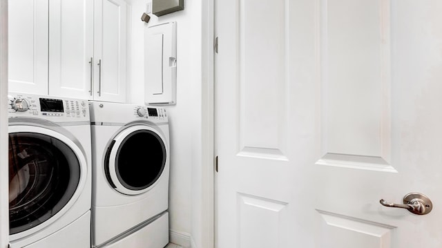 laundry area featuring cabinets, washing machine and clothes dryer, and electric panel