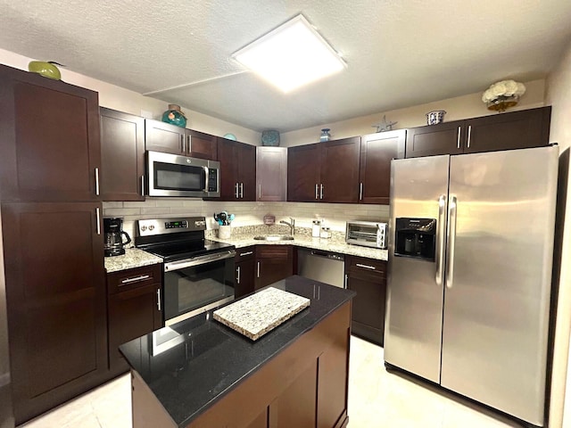 kitchen with sink, tasteful backsplash, dark brown cabinets, a textured ceiling, and appliances with stainless steel finishes