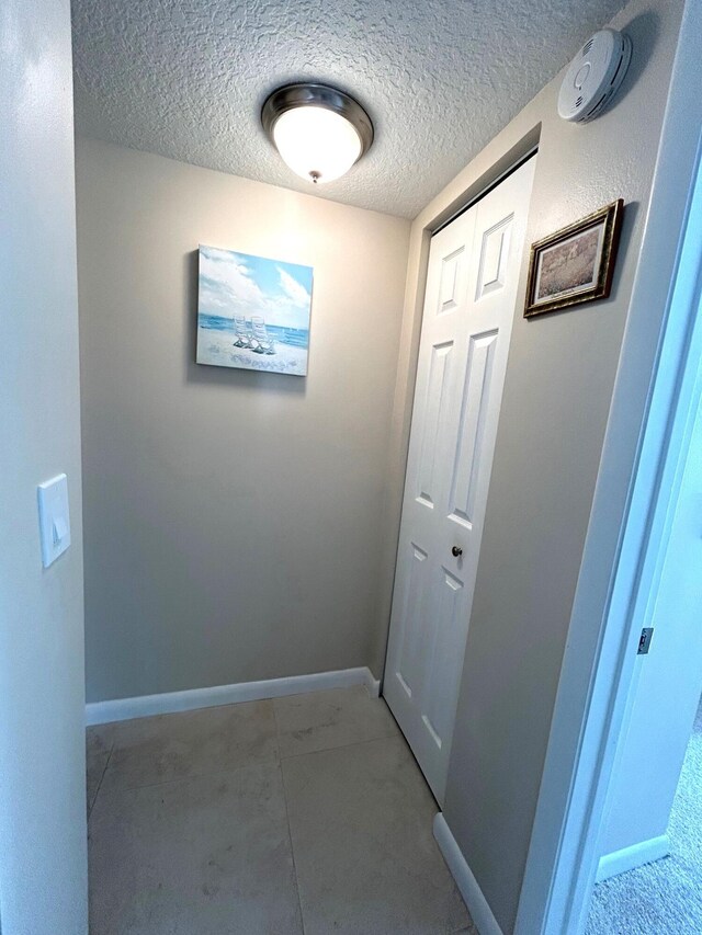 bedroom featuring connected bathroom, light colored carpet, and a textured ceiling