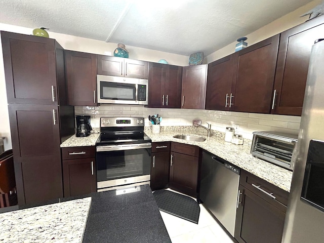 kitchen featuring appliances with stainless steel finishes, sink, backsplash, and light stone counters