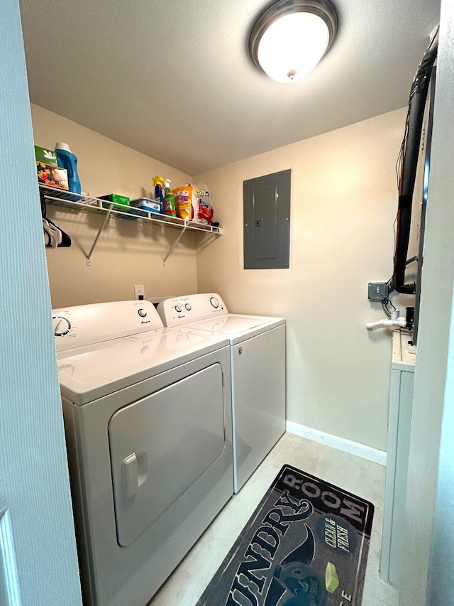 laundry area featuring light tile patterned floors, washing machine and dryer, and electric panel