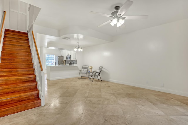 unfurnished living room with ceiling fan with notable chandelier