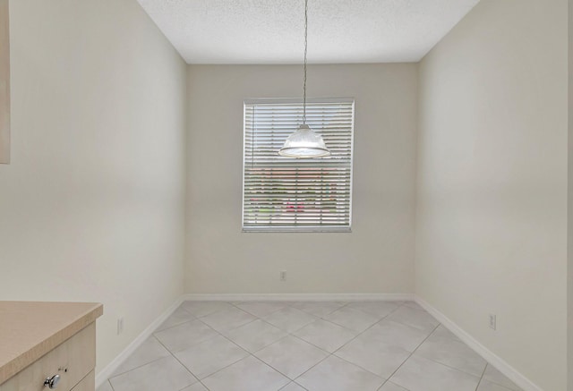 unfurnished dining area featuring a healthy amount of sunlight, a textured ceiling, and light tile patterned floors