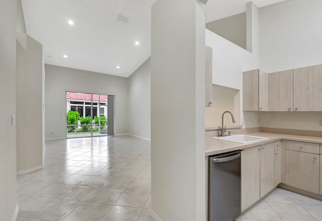 kitchen featuring a towering ceiling, dishwasher, sink, and light brown cabinets