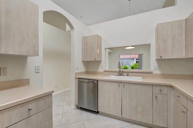 kitchen featuring light tile patterned flooring, stainless steel dishwasher, light brown cabinetry, and sink