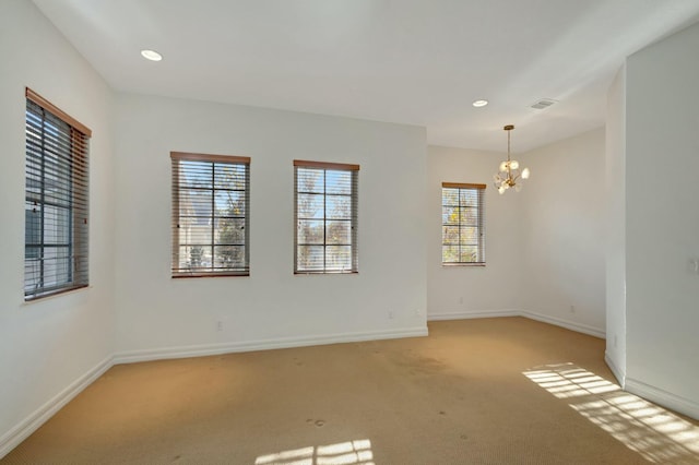 carpeted empty room with a chandelier