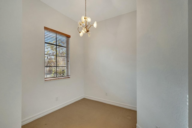 carpeted spare room with an inviting chandelier