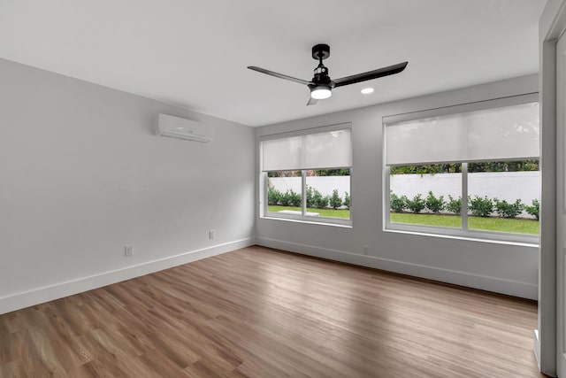 unfurnished room with ceiling fan, a wall mounted AC, and light wood-type flooring