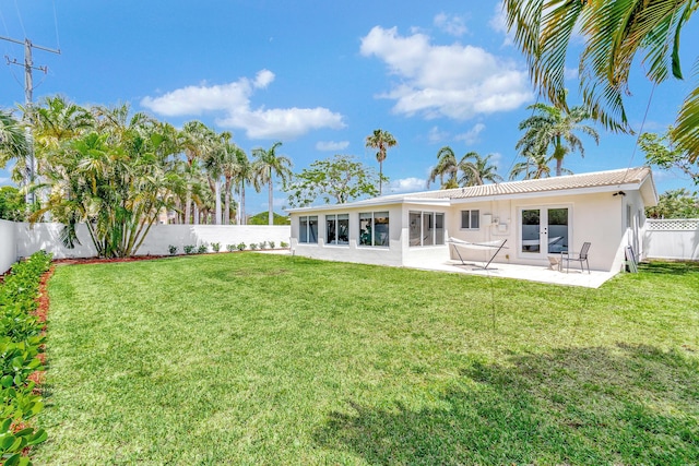 back of house with a patio and a lawn