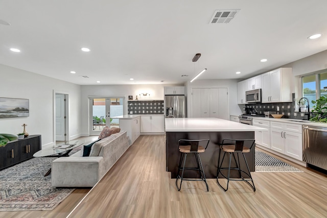 kitchen featuring sink, stainless steel appliances, white cabinets, and a kitchen island