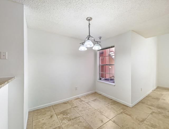 unfurnished dining area with tile patterned flooring, a textured ceiling, and a notable chandelier