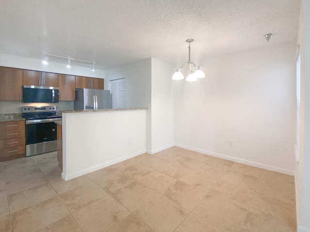 kitchen with light tile patterned floors, stainless steel appliances, a textured ceiling, decorative light fixtures, and a chandelier