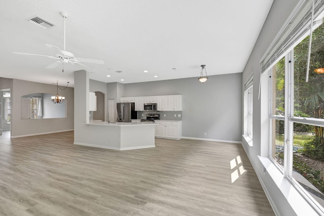 unfurnished living room featuring ceiling fan with notable chandelier and light wood-type flooring