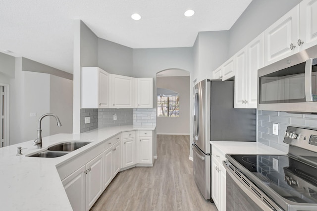 kitchen featuring sink, appliances with stainless steel finishes, white cabinetry, tasteful backsplash, and light wood-type flooring