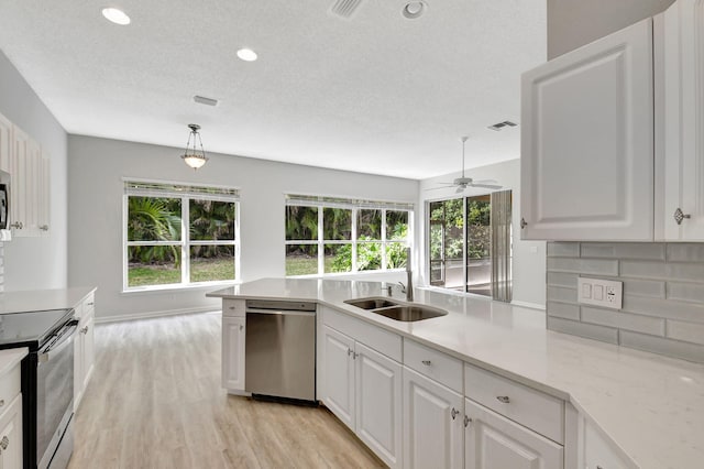 kitchen featuring sink, light wood-type flooring, pendant lighting, stainless steel appliances, and white cabinets